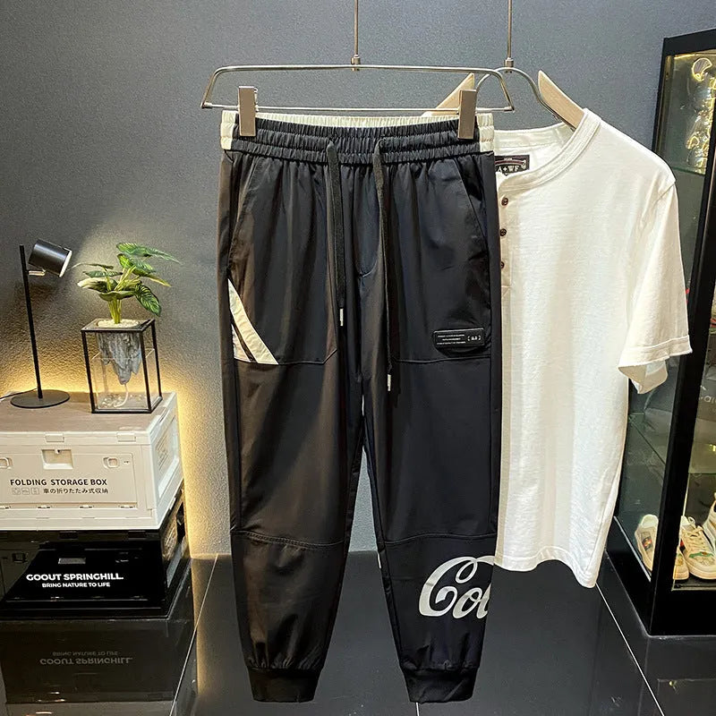 Black men's casual cotton trousers with cropped legs and an ankle band on a solid background.