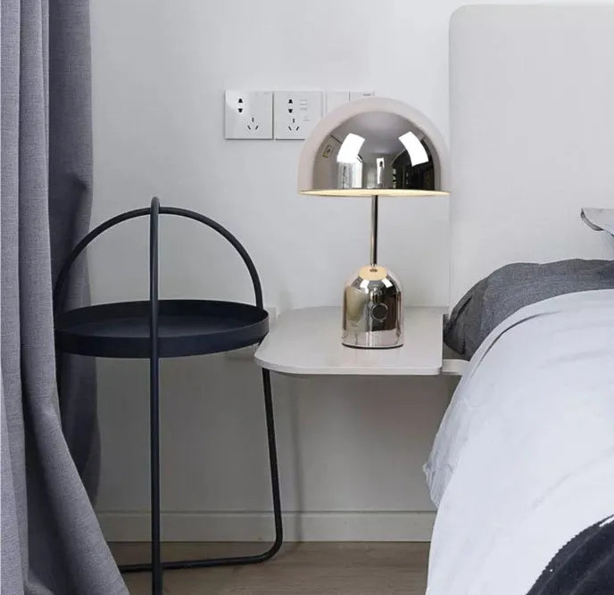 Mushroom-shaped table lamp with a metal base in rose gold finish on a wooden table.