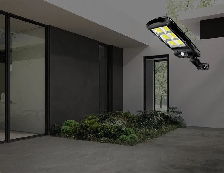 Black outdoor solar motion sensor wall light mounted on fence with LED illumination