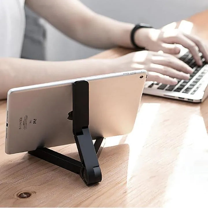 Black foldable tablet holder supporting a smartphone in landscape viewing mode on a desk.