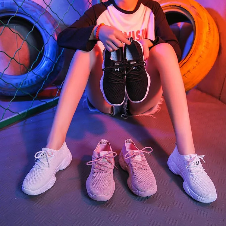 Women's white fly knit slip-on sport shoes with a thick rubber sole and front strap.