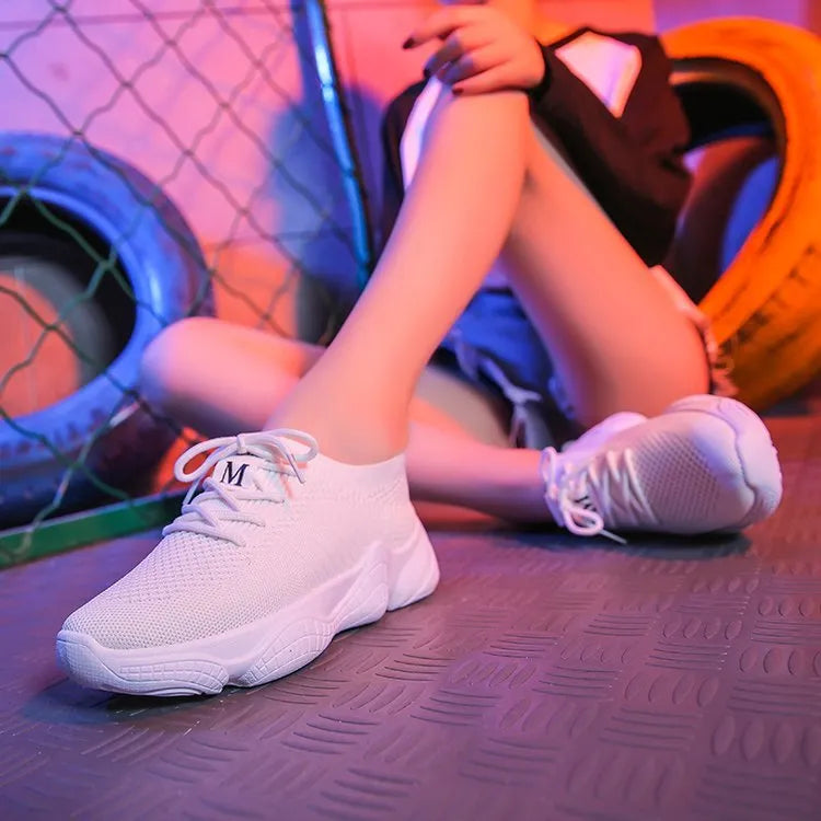 Women's white fly knit slip-on sport shoes with a thick rubber sole and front strap.
