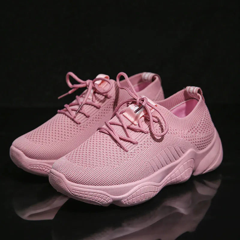 Women's white fly knit slip-on sport shoes with a thick rubber sole and front strap.