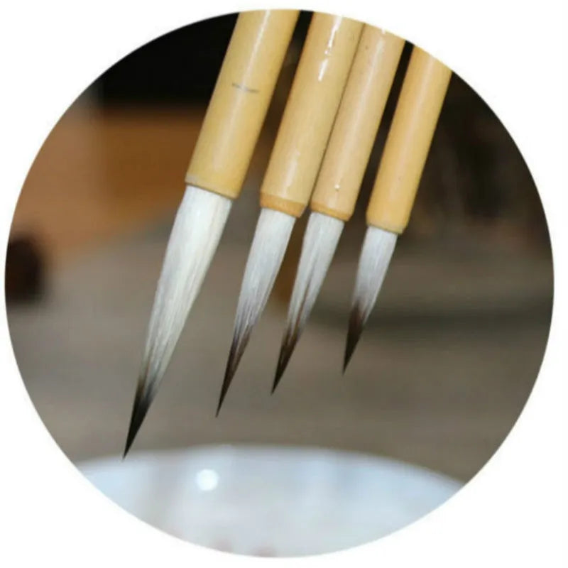 Set of four gold-handled writing brushes with mixed hair bristles for calligraphy.