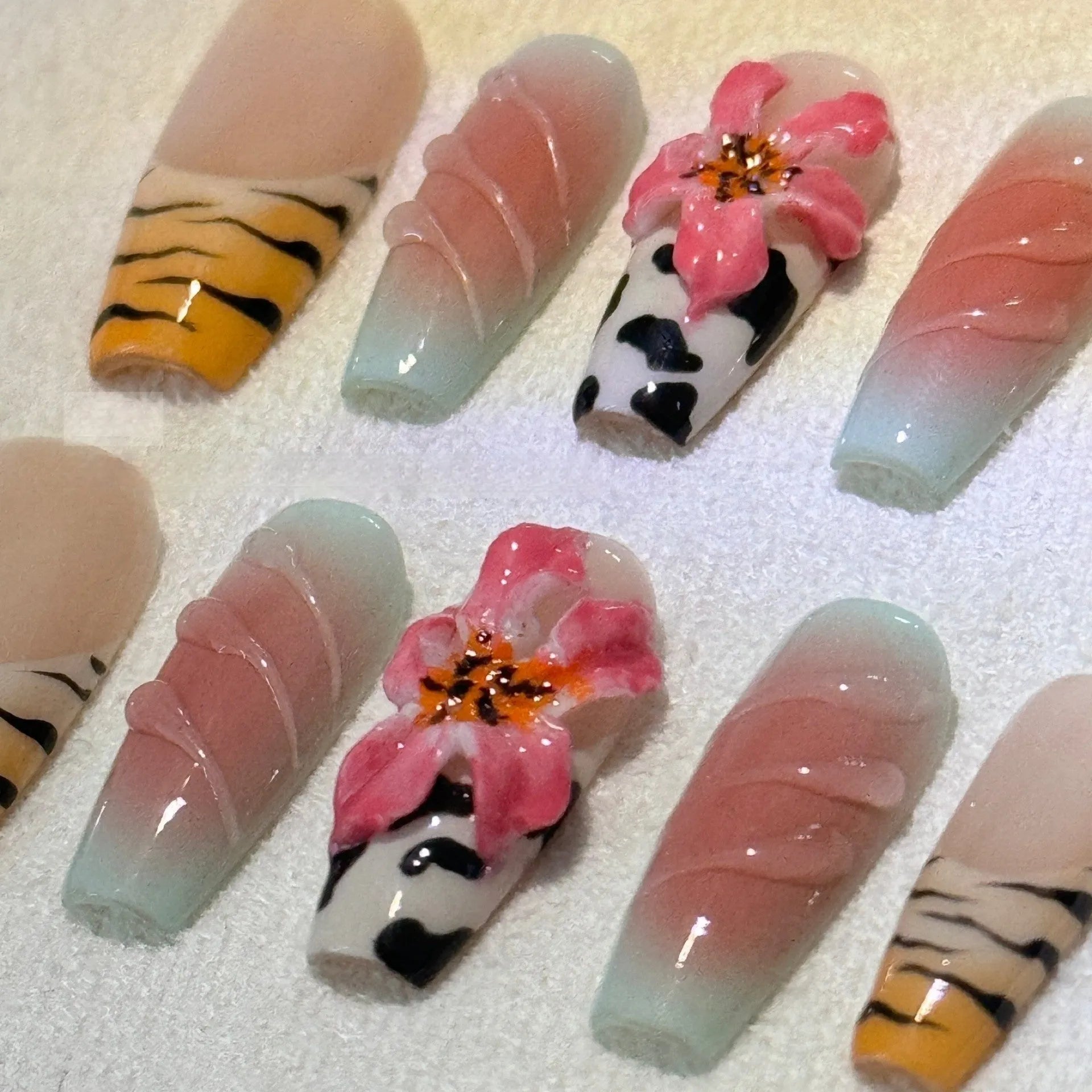 Hand-carved artificial nails with raised zebra pattern and floral designs, shown in long style.