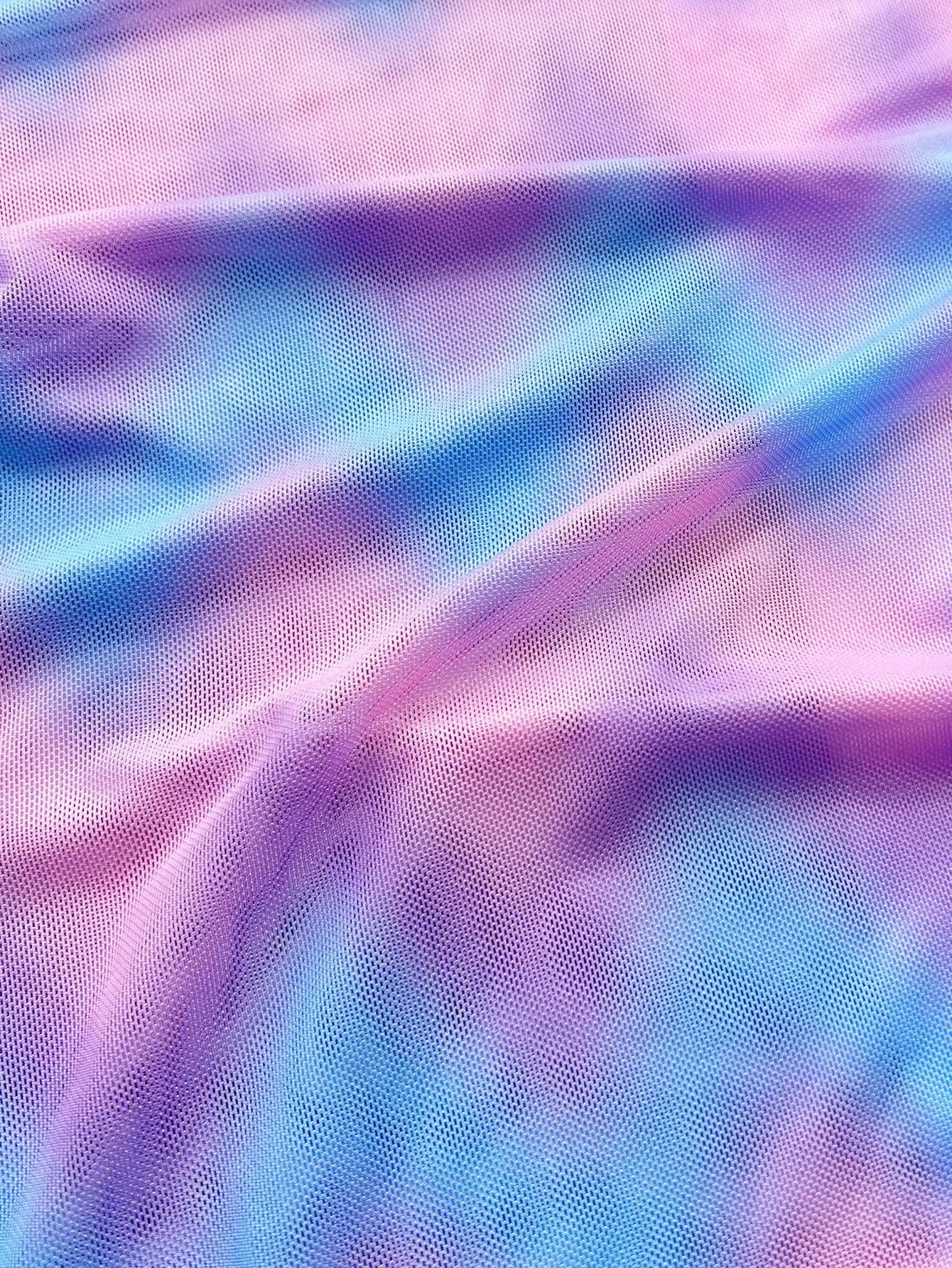 Women's tie-dye pattern bikini set with matching skirt on a neutral background.
