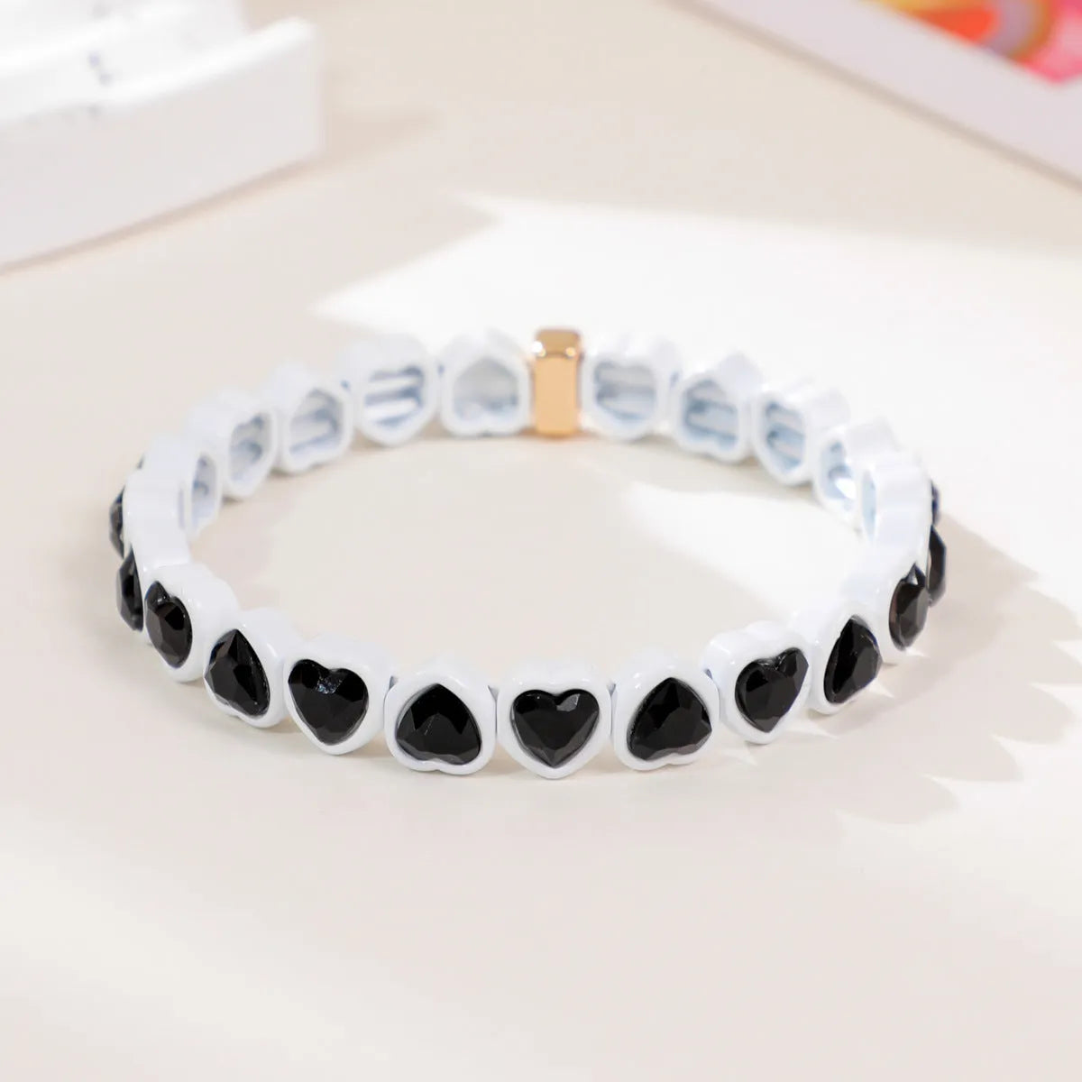 Colourful enamel finish alloy heart charm on a black stretch bracelet band.