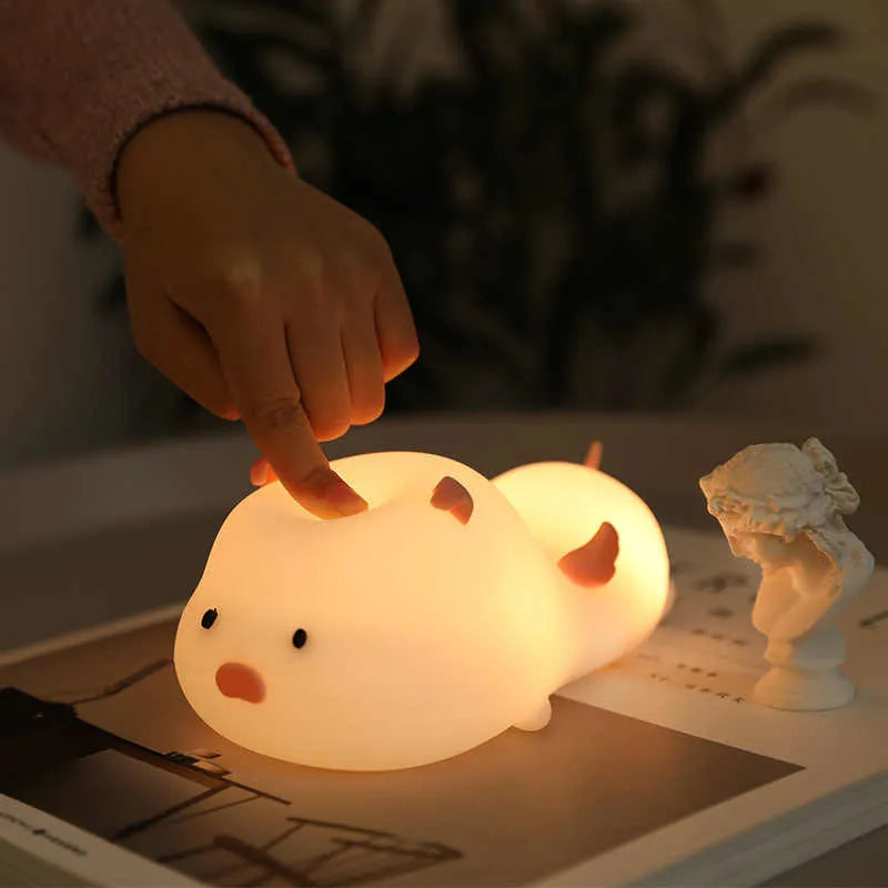 Pink silicone pig-shaped night light with touch control on bedside table