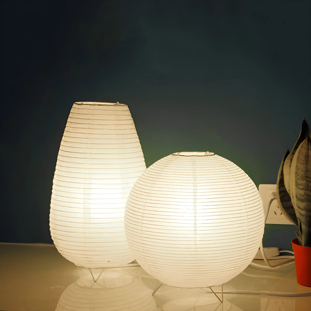 White rice paper plug-in table lamp in circular shape on a wooden bedside table.