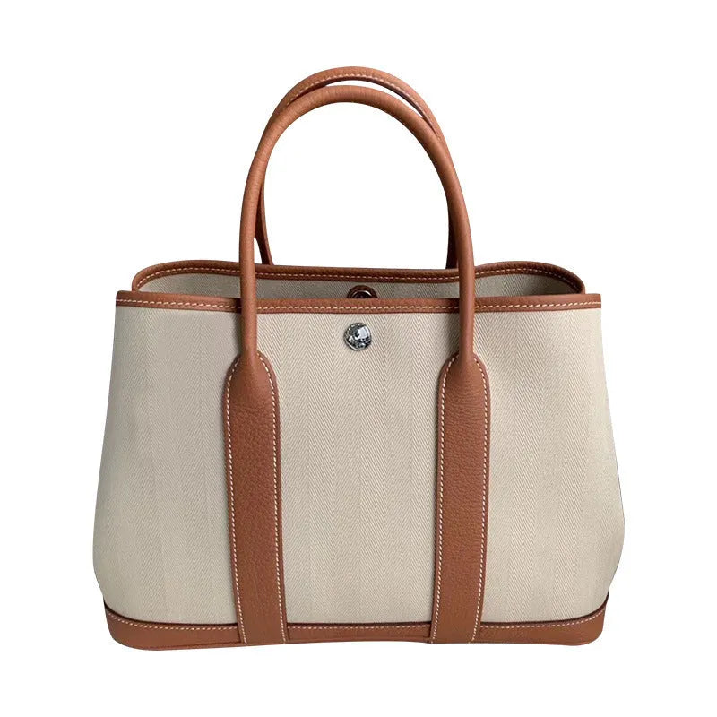 Women's genuine leather crossbody tote bag with canvas trim in bucket shape showing internal document and zipper compartments