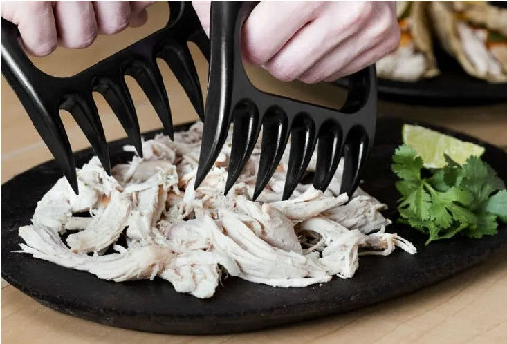 Two black PC bear claw meat shredders on a cutting board, ready for barbecue use