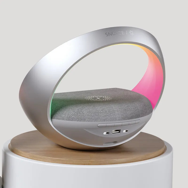 Beige wireless charging pad with digital clock, Bluetooth speaker, and ring of RGB LED mood lights.