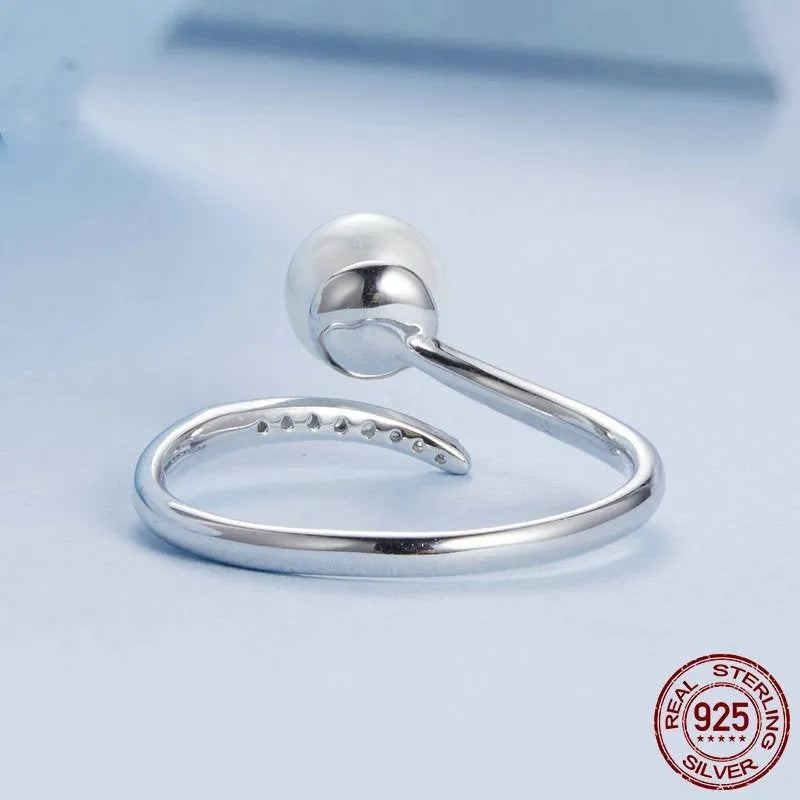 Adjustable sterling silver ring with a white shell pearl centre on an open loop band.