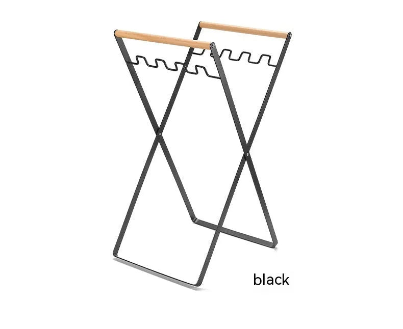 Foldable black wrought iron garbage storage hanger with a wooden handle, shown holding a bin bag.