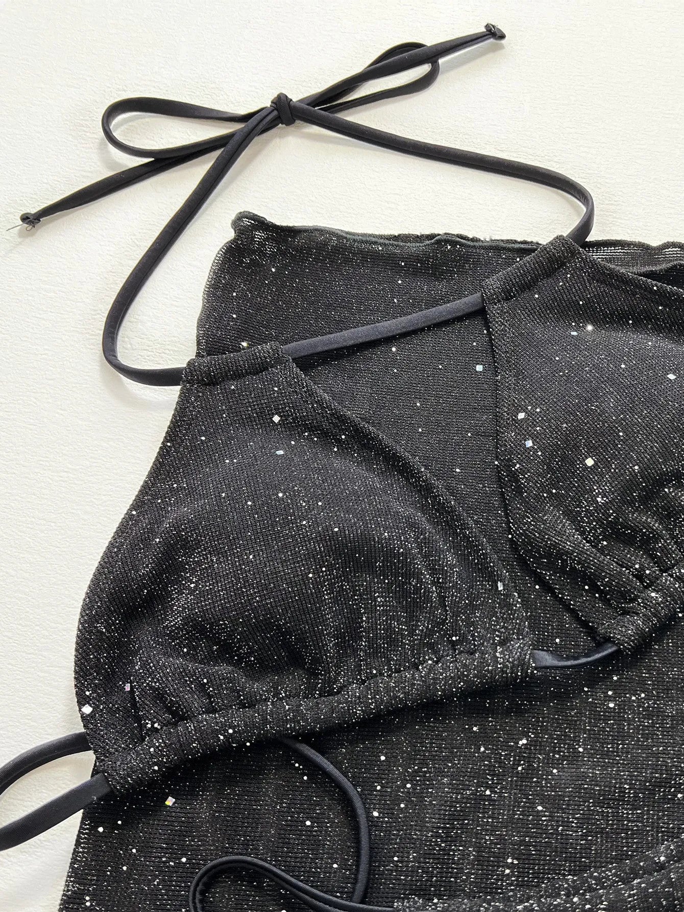 Black three-piece bikini swimsuit set with a top and shorts on a mannequin.