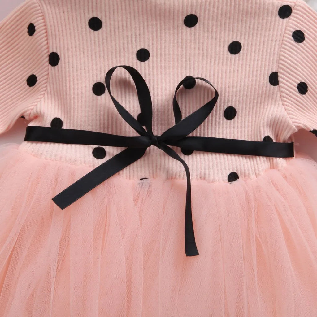 Baby girl wearing a long sleeve white lace tutu dress for a christening or birthday party.