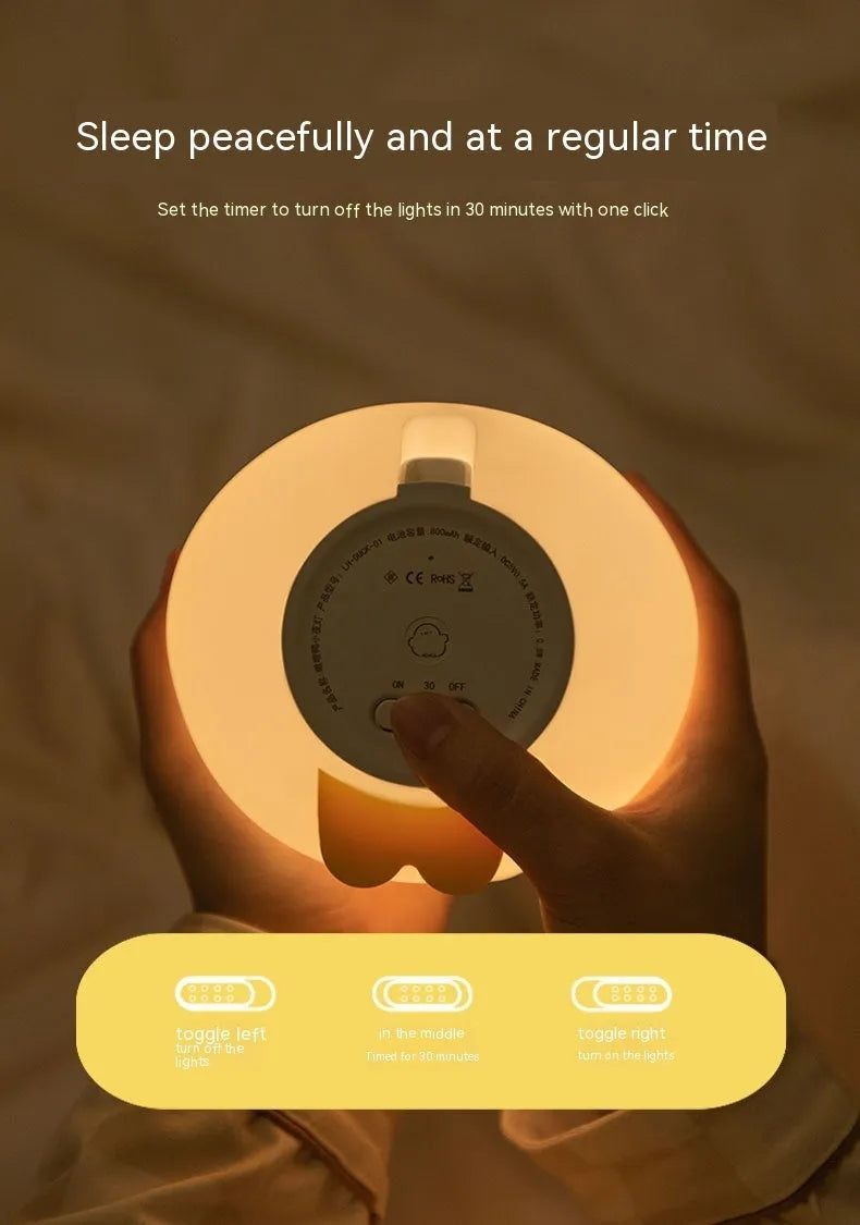 Cute duck shaped LED night lamp with silicone casing and warm light on a bedside table