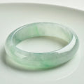 Light green jade bead bracelet showing natural stone texture with sizing options from 53mm to 64mm