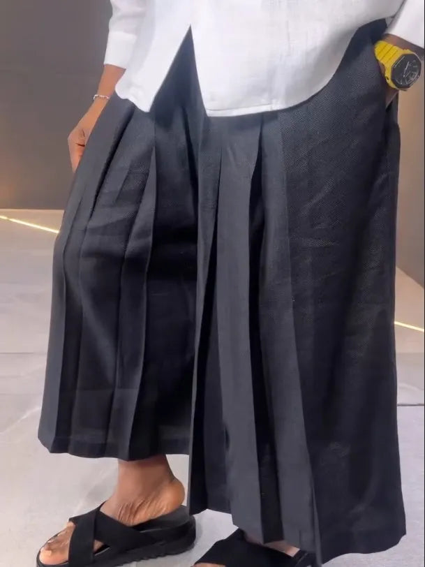 White asymmetric front long sleeve shirt paired with black pleated pants in a women's casual co-ord set.