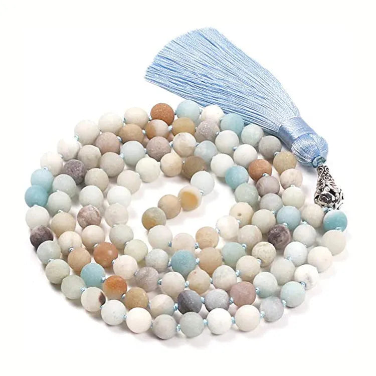 Long beaded agate and amethyst tassel necklace with geometric pendant on a neutral background.