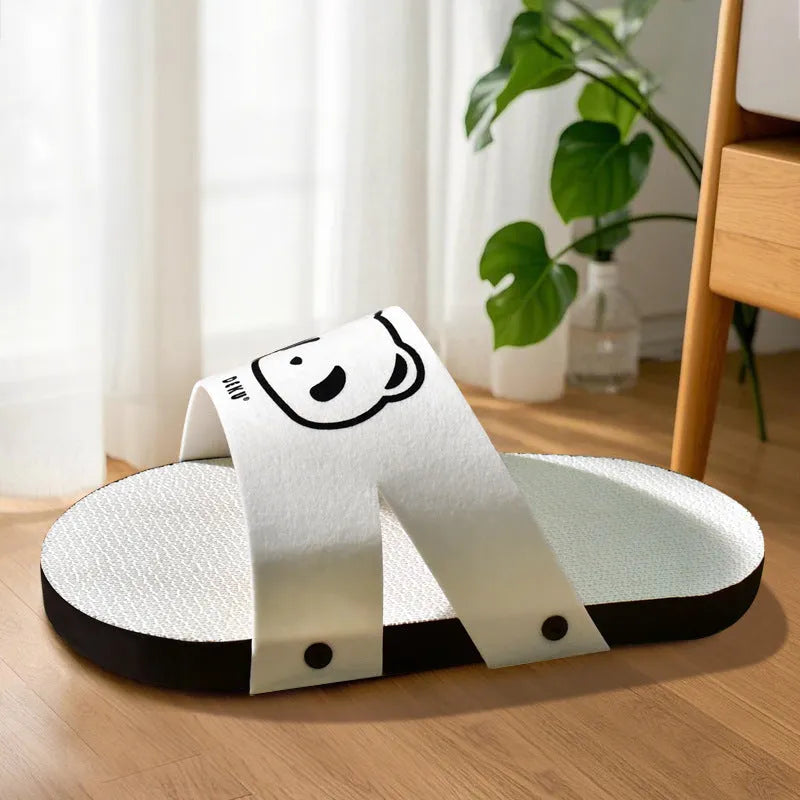 White corrugated paper cat scratch board in a slipper shape on a floor.