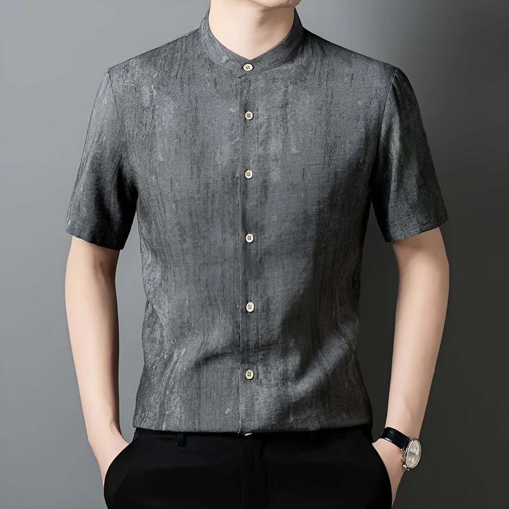 Man wearing a loose grey short sleeve cardigan shirt with a stand collar.