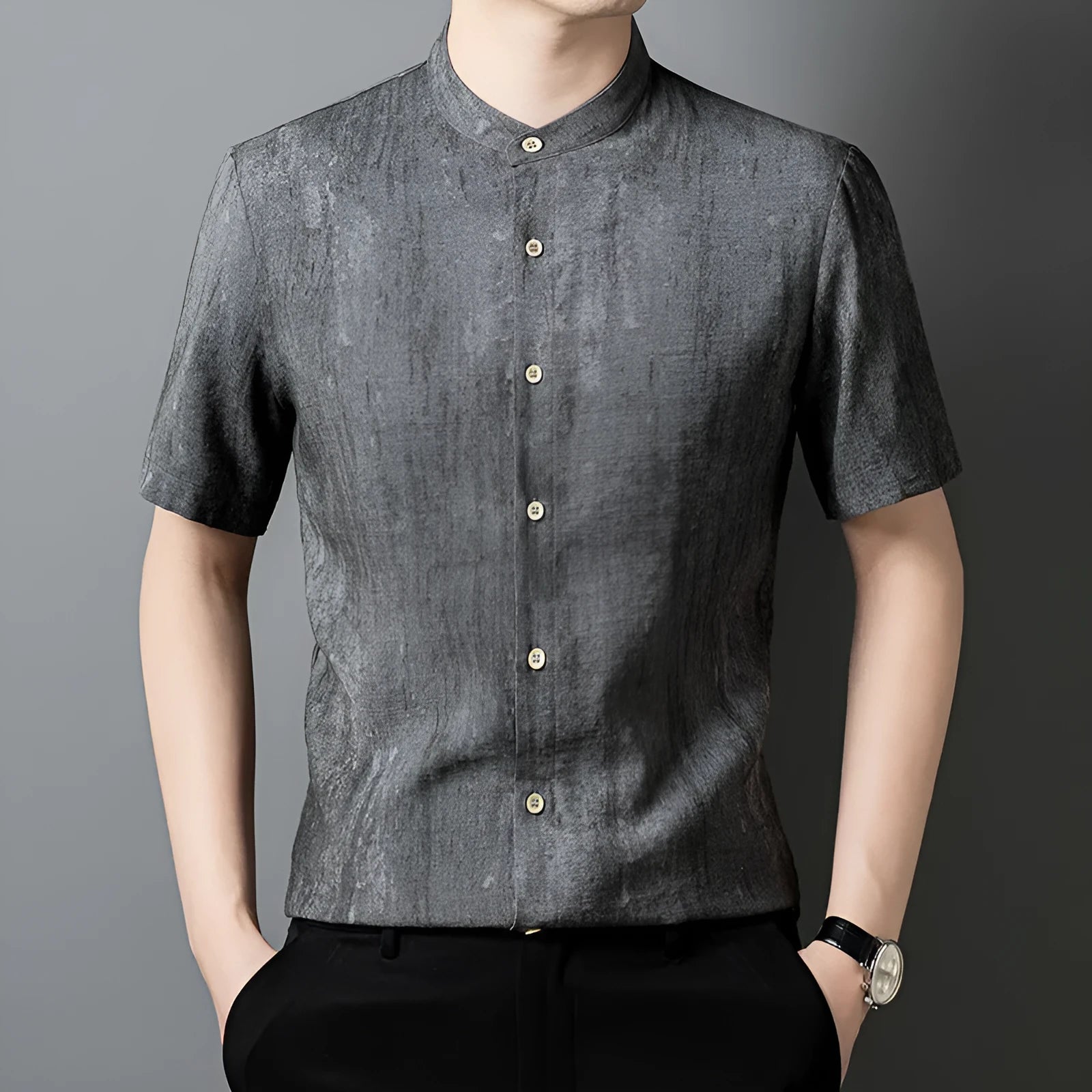 Man wearing a loose grey short sleeve cardigan shirt with a stand collar.