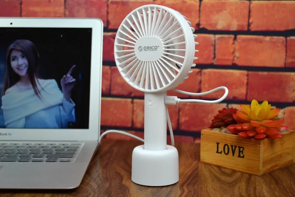 White ORICO FH1 USB rechargeable desk fan with fine-line texture on a desk, showing compact size.