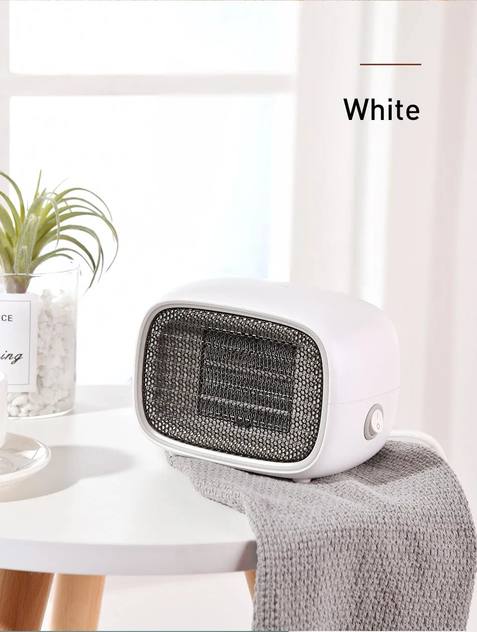 Green mini ceramic space heater with EU plug on a wooden desk