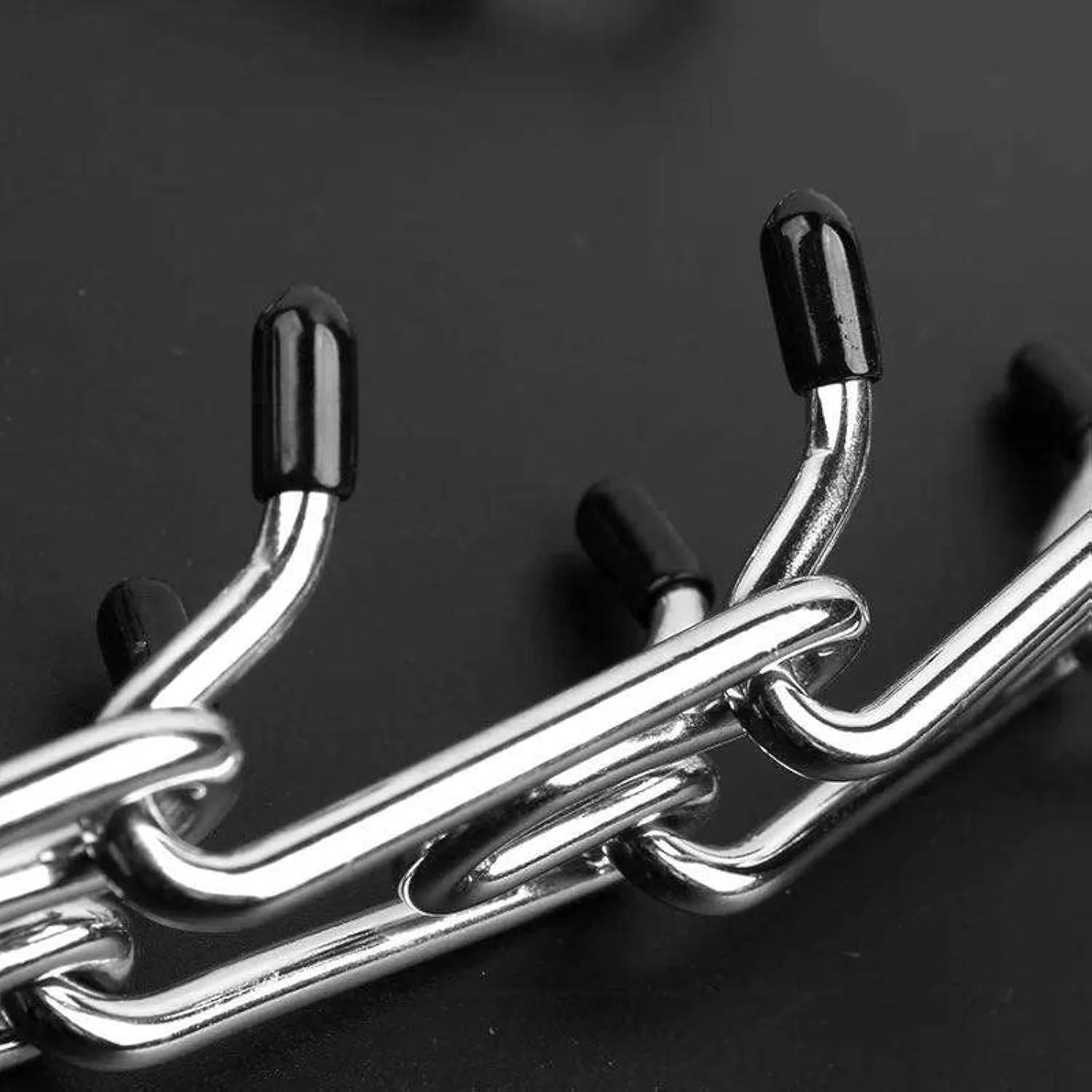 Stainless steel dog prong collar with rubber tips and adjustable chains on a grey background.