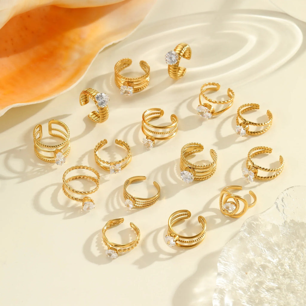 Gold electroplated stainless steel ring with zircon details in heart and geometric shapes on a grey background.