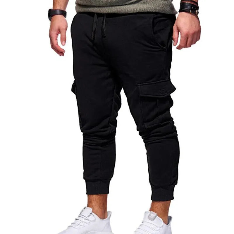 Men sport jogger pants in black with elastic waistband and tapered legs, made from polyester Lycra stretch fabric