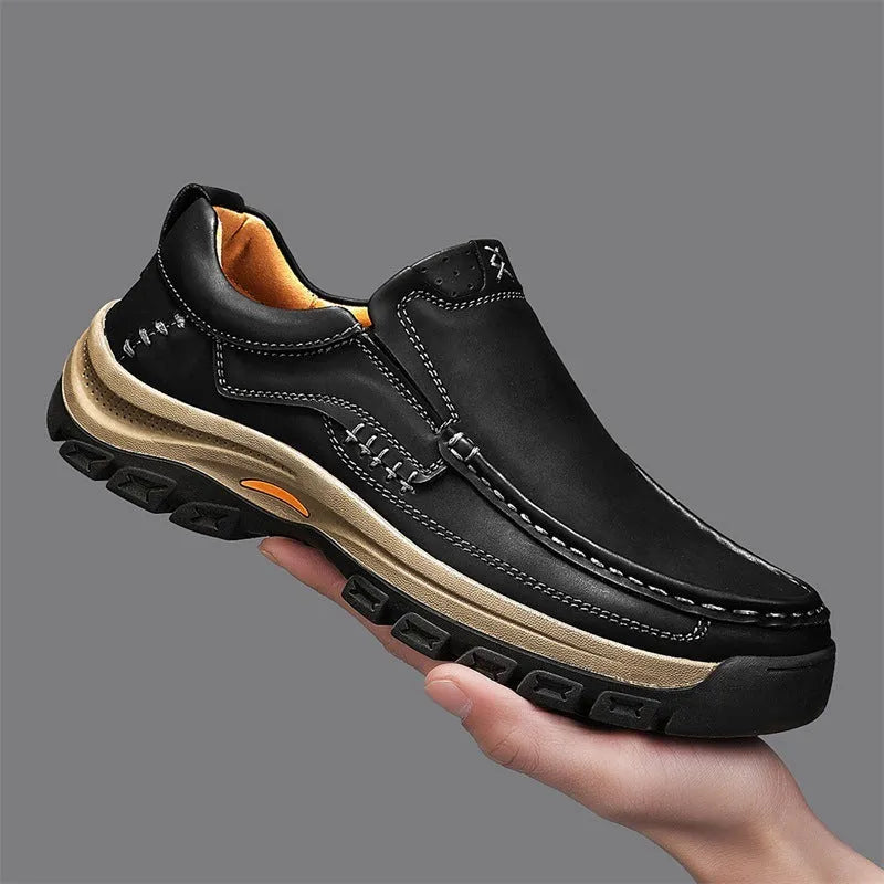 Men's black thick-soled mountaineering leather shoes with round toe and visible stitching on a natural background.