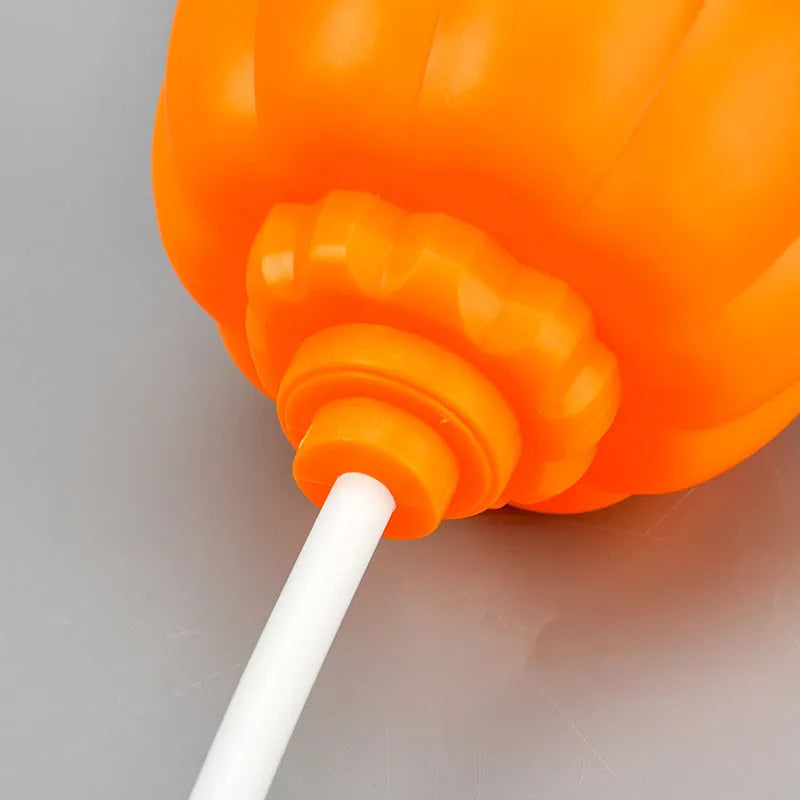 A plastic pumpkin lamp with a USB port, glowing in either yellow or purple light.