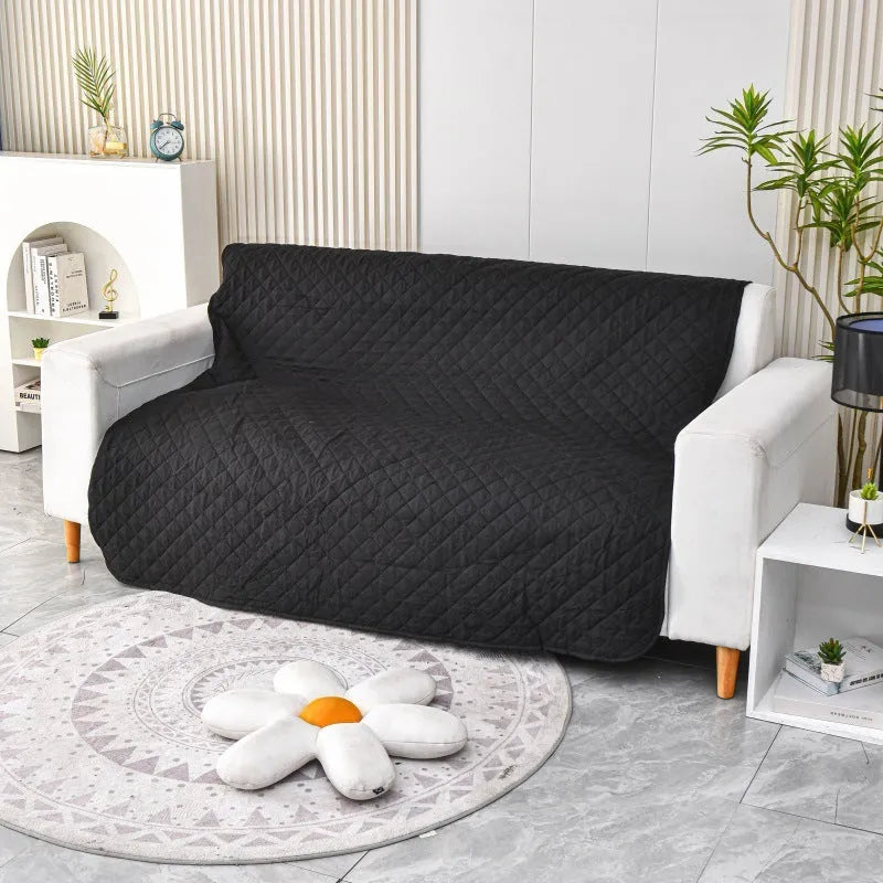 Reversible dog blanket on a sofa, showing two colour options, protecting furniture from pets.