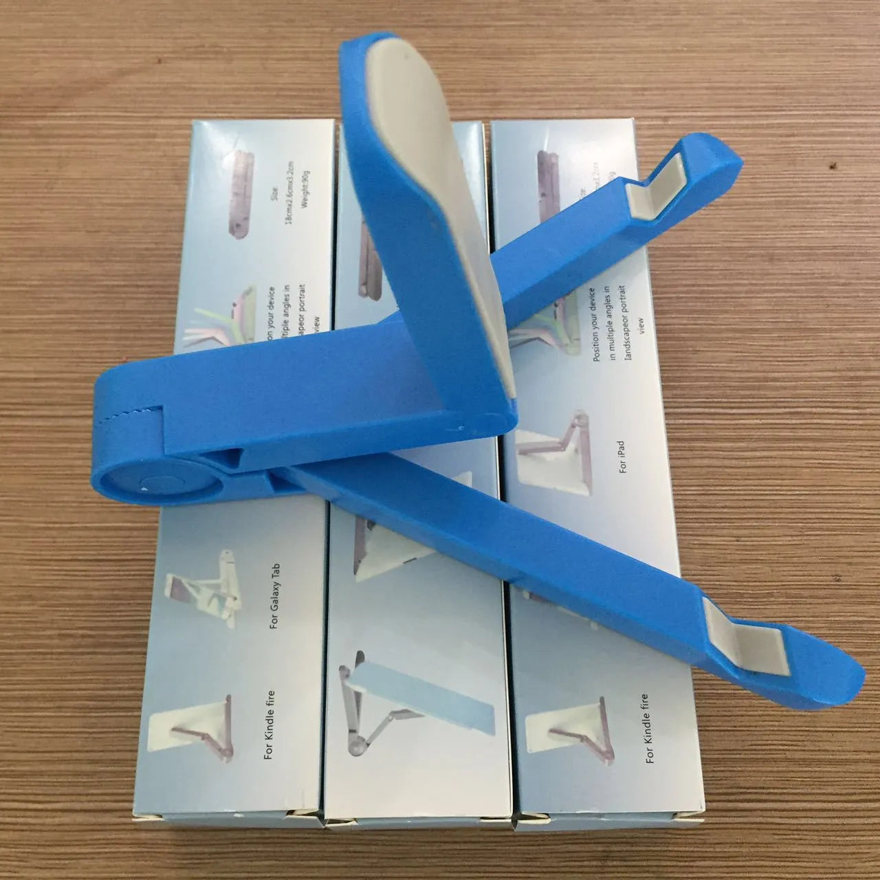Black foldable tablet holder supporting a smartphone in landscape viewing mode on a desk.