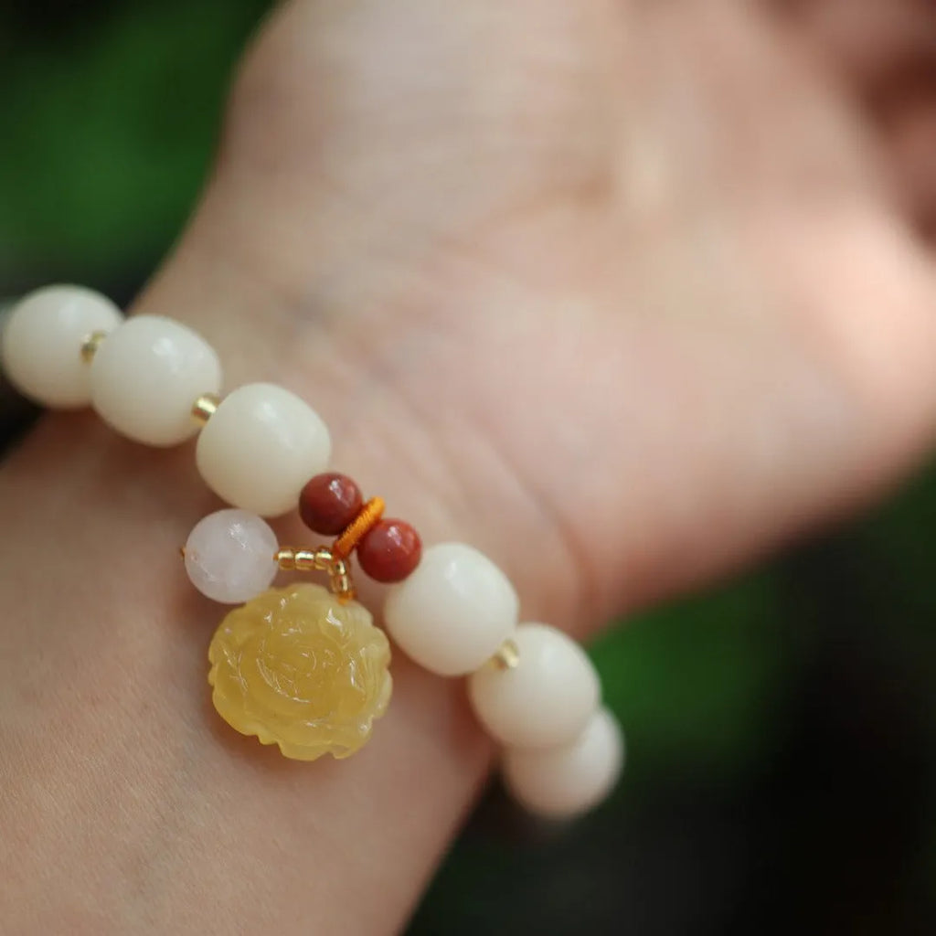 Close-up of a woven gradient white jade and Bodhi root bracelet with flower-shaped beads and a lotus accent.
