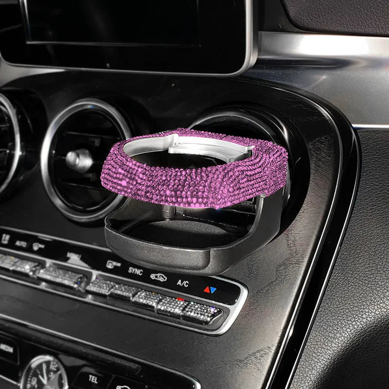 White diamond rhinestone car air vent cup holder bracket on a grey car dashboard.