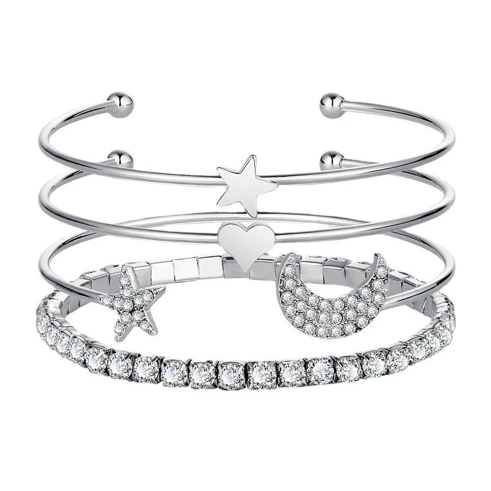 Four gold and silver metal cuff bracelets with moon and star designs on a plain background