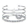 Four gold and silver metal cuff bracelets with moon and star designs on a plain background