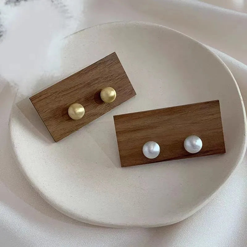 Pair of matte brushed gold bean shaped stud earrings for women with gold and white finish
