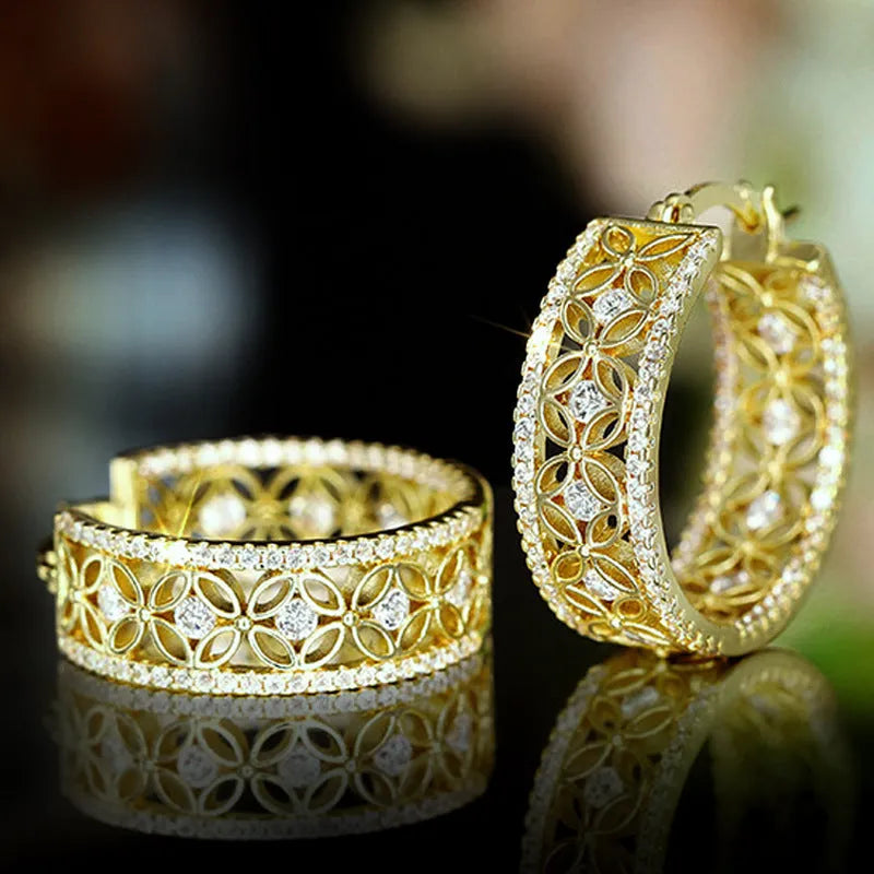 A pair of gold-coloured geometric butterfly earrings with floral details and horse eye styling on a white background.