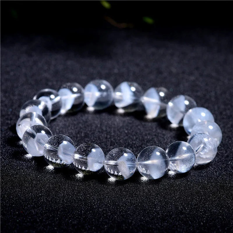 Women's white crystal pyramid bracelet with Ruyi symbols on wrist, showing ground bead texture.