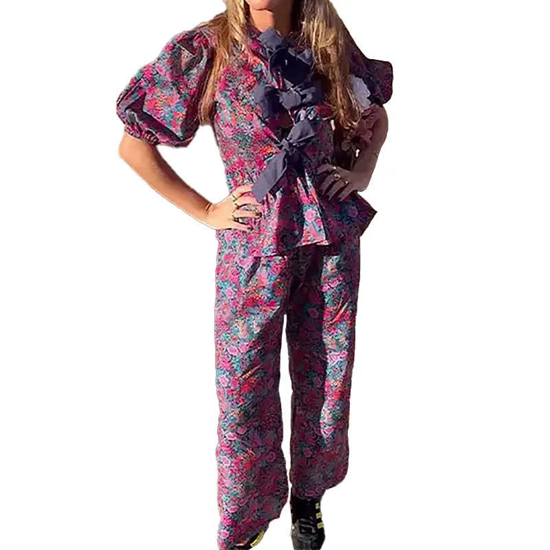 Women's floral print polyester trouser suit with puff sleeve blouse and matching trousers on a hanger.
