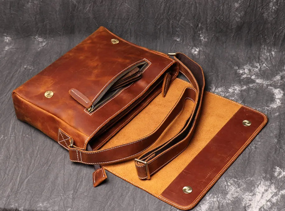 Brown vintage leather men's messenger bag with a shoulder strap showing internal organiser pockets.