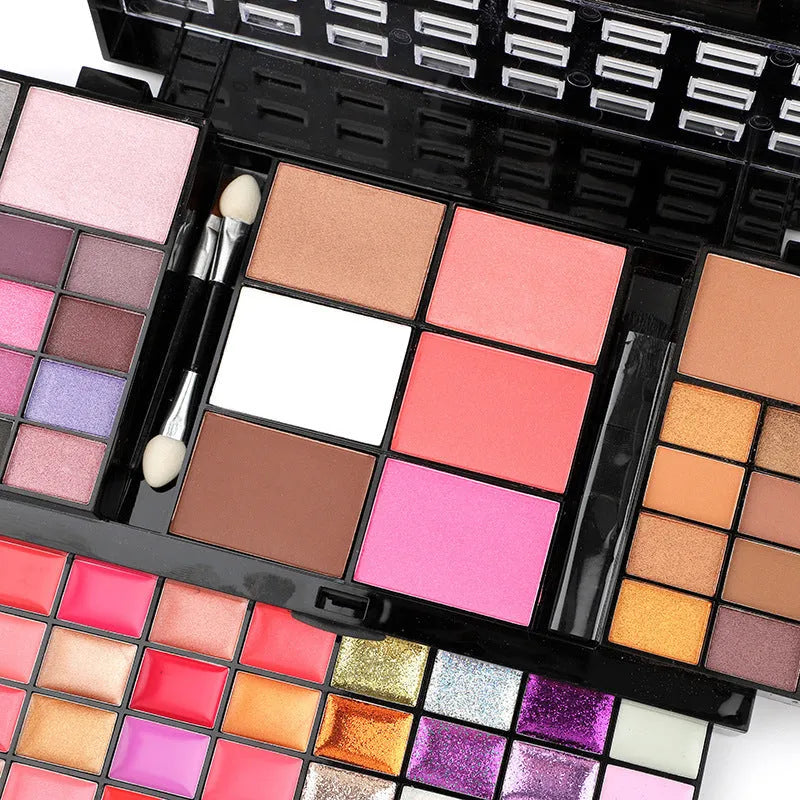 74 colour makeup palette open showing four layers of eyeshadow, lip gloss, blush and contour powders with included brushes.