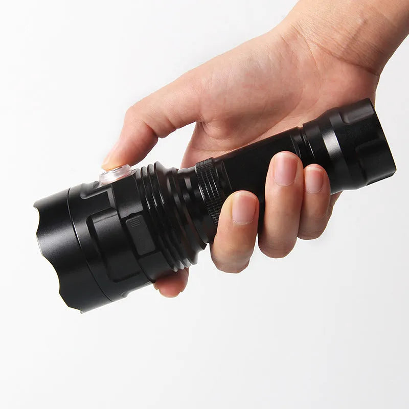 Black aluminium alloy LED flashlight with large head, shown with USB cable and yellow packaging box.