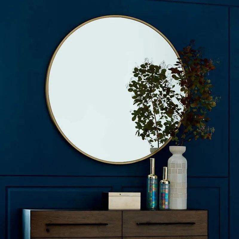 Round metal wall mirror in black finish, shown on a bathroom wall.
