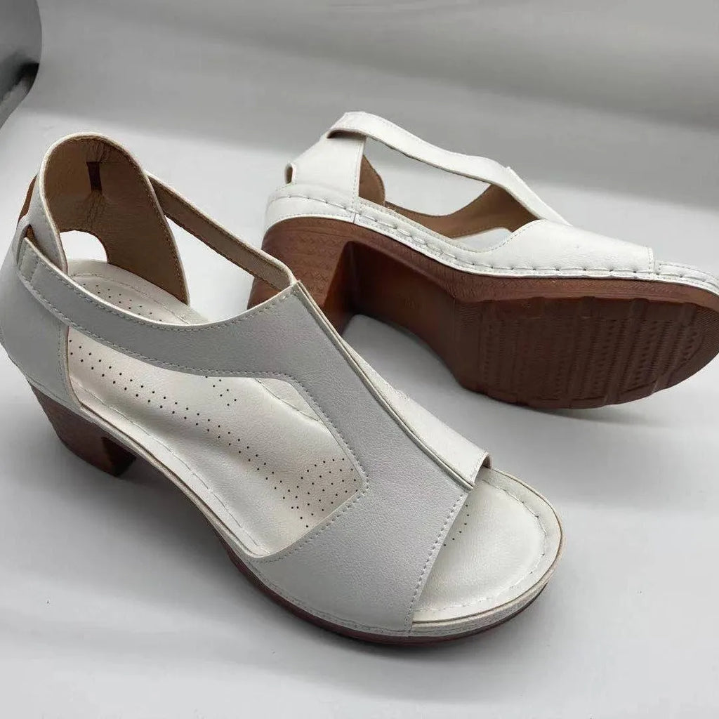 Women's beige peep toe wedge sandals with ankle buckle, shown on a foot.