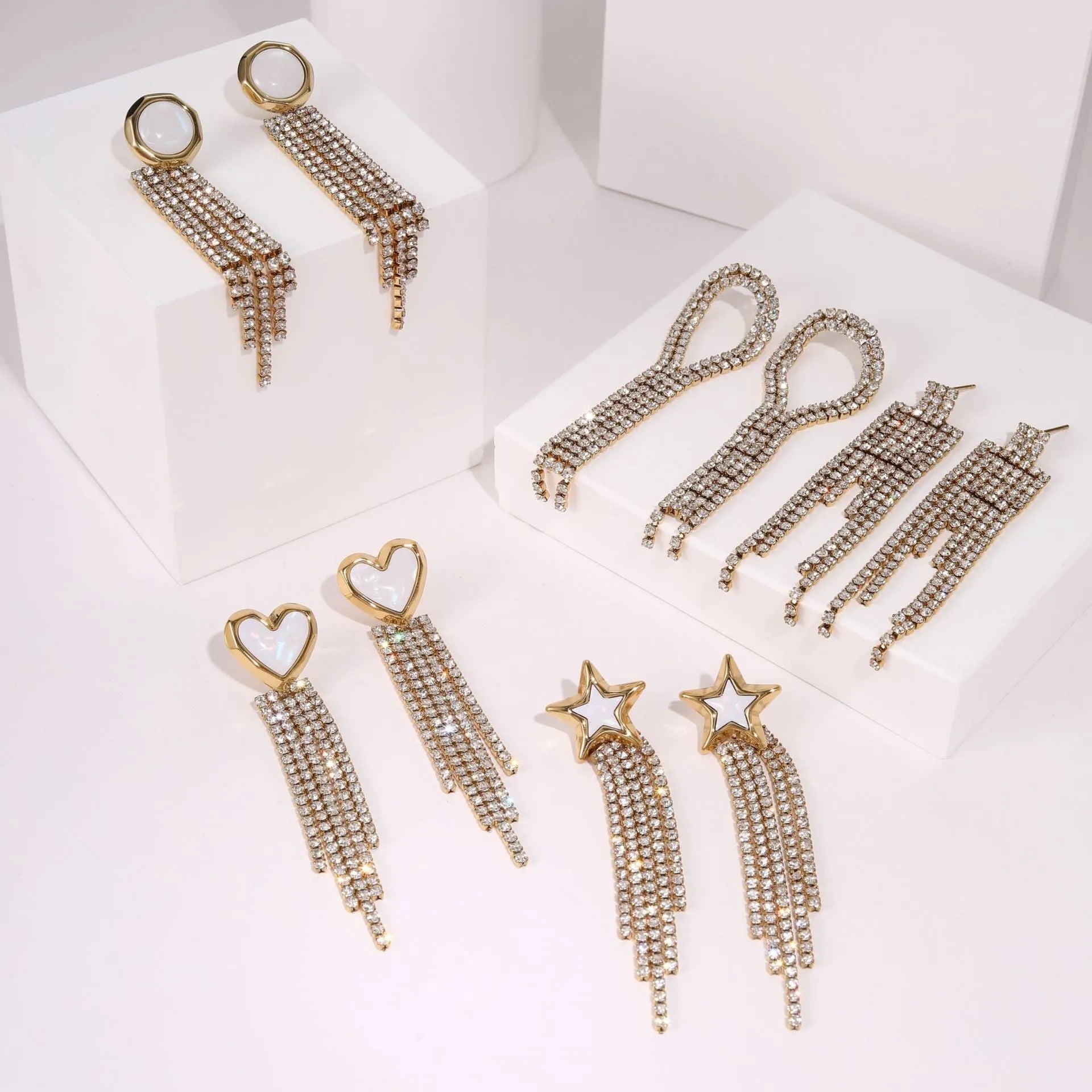 Gold electroplated stainless steel earrings with heart, star, and geometric shapes and a diamond tassel pendant.